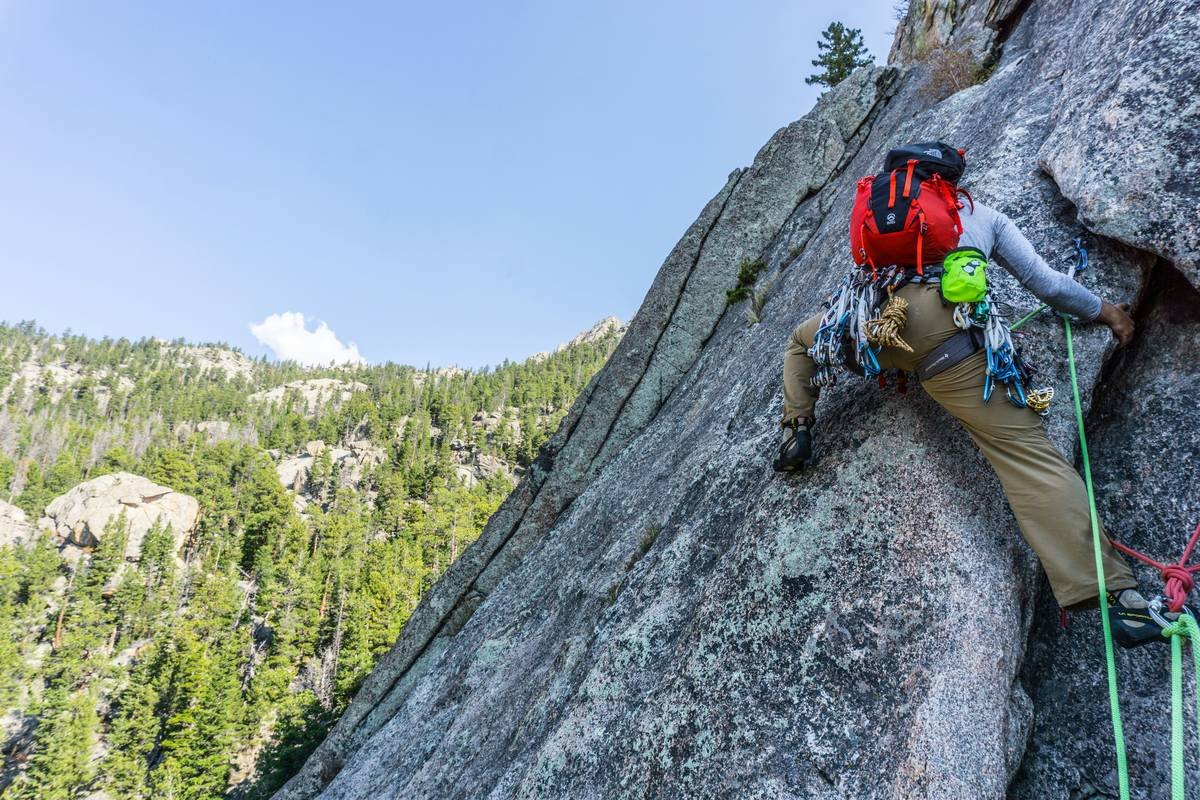 A pair of climbing gloves resting on a rocky surface near climbing equipment