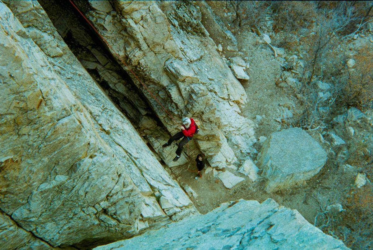 A climber wearing protective gloves scaling a rugged rock face