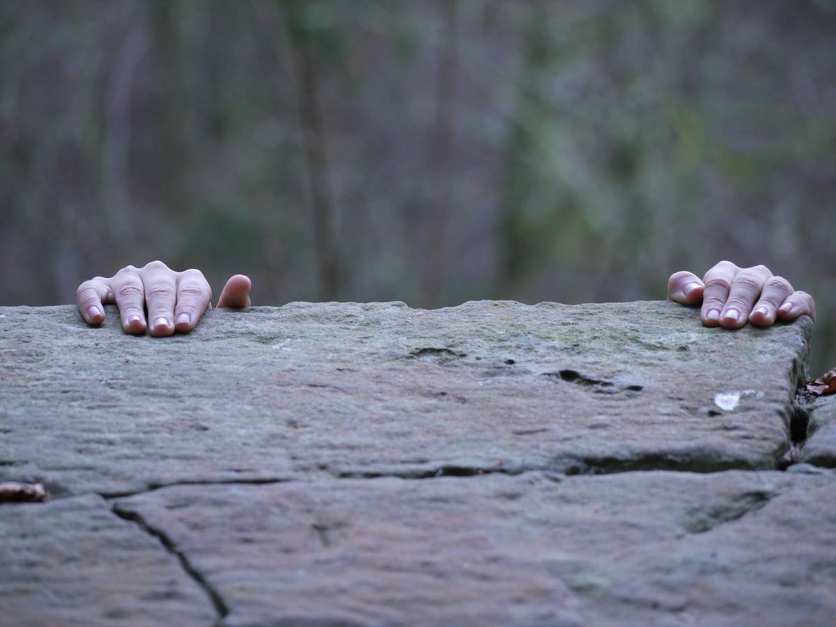 A climber wearing high-quality climbing gloves, looking focused and determined at the base of a cliff.